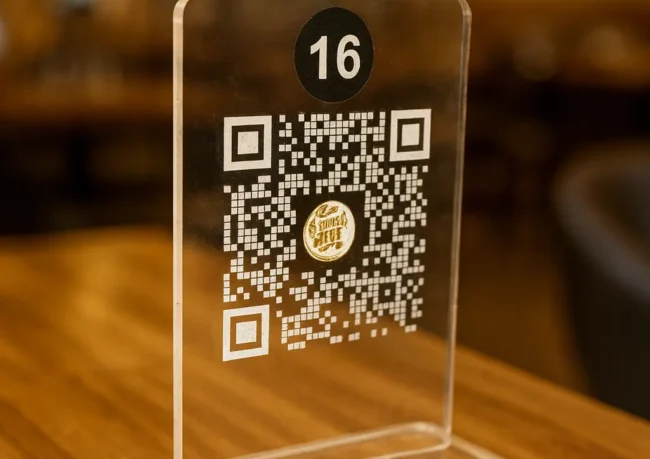 Restoran masasında duran şeffaf pleksi QR kodlu menü numarası – dijital temassız menü çözümü
